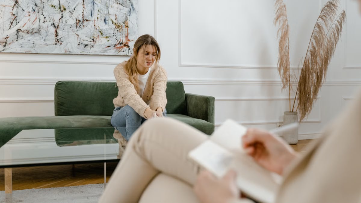 A woman during a therapy session in a modern living room setting, expressing concern.